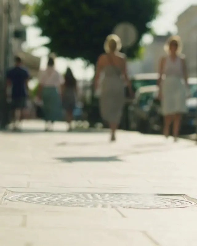 A sunlit street with people walking.