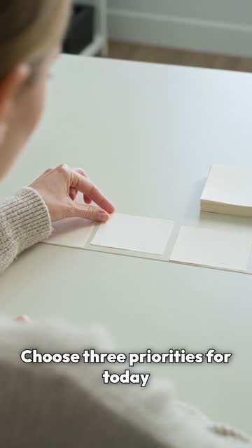 Over-the-shoulder view of a person in a knit sweater arranging cards on a white desk.
